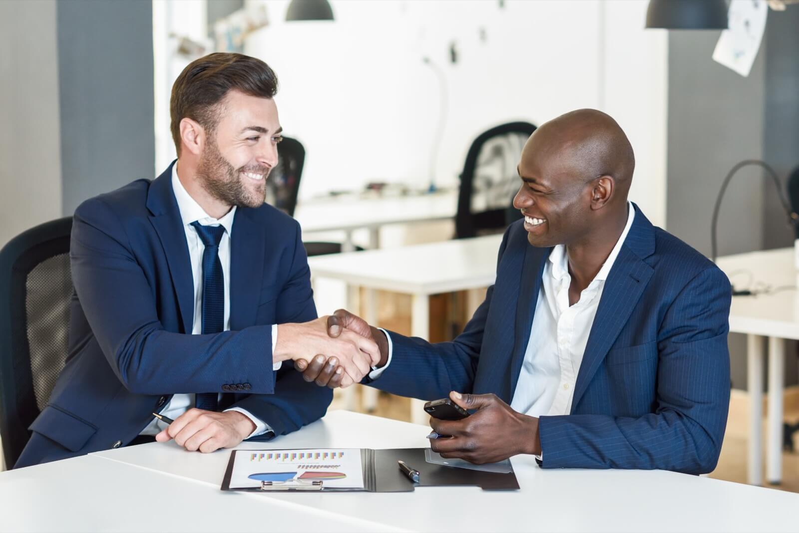 Two colleagues shaking hands over a business meeting, representing the clear path to becoming an FSO