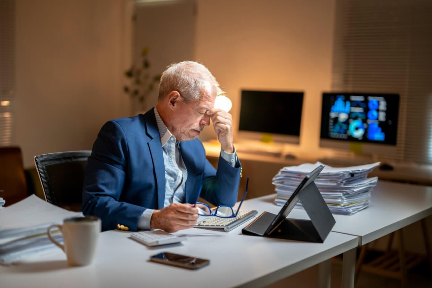 Overwhelmed executive buried in stacks of paperwork, representing the compliance administrivia FSOs lose hours to every month