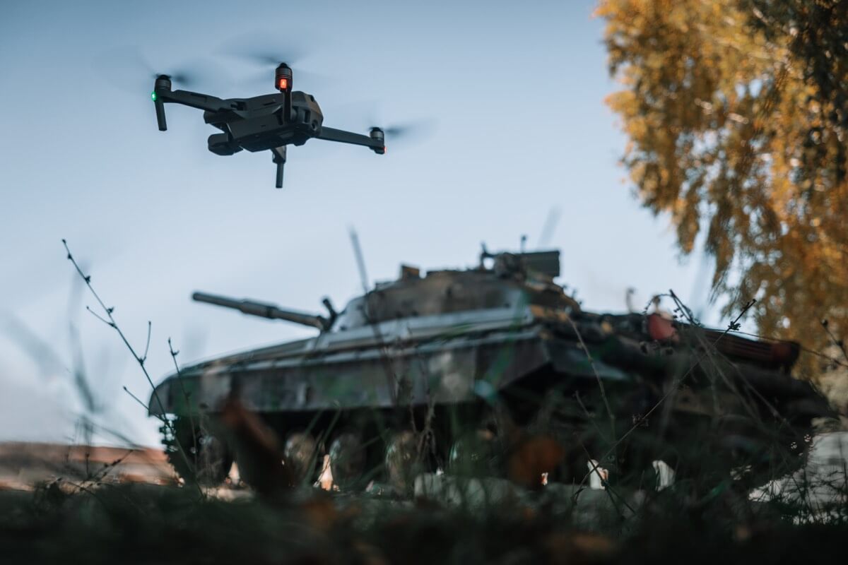 Drone technology operating near armored defense equipment, reflecting the cleared defense industry Thrive Analysis Group serves